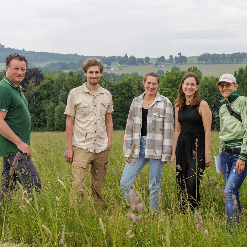 Das Team von PRIMAKLIMA steht auf einer aufgeforsteten Fläche.